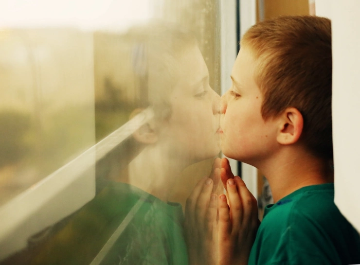 Autista kisfiú kifelé bámul az ablakon