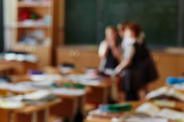 Elhomályosított kép: osztályterem táblával, tanulókkal